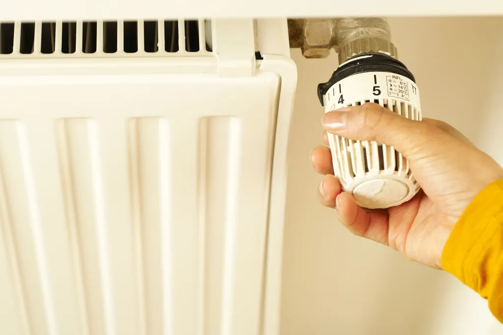 Main réglant le robinet thermostatique d’un radiateur