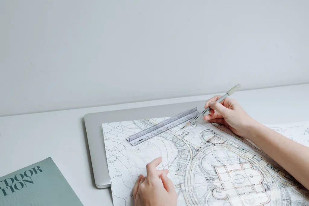 Mains traçant un plan d’architecte sur une table
